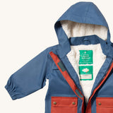 A close up of the Little Green Radicals waterproof coat in moonlight blue Showing the sherpa fleece liner and name patch detail on blue recycled polyester fabric