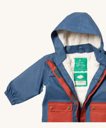 A close up of the Little Green Radicals waterproof coat in moonlight blue Showing the sherpa fleece liner and name patch detail on blue recycled polyester fabric