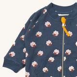 A close up of the Little Green Radicals reversible easy rider jacket in sleeping sheep. Showing the zip detail which features a yellow toggle for easy opening and closing 