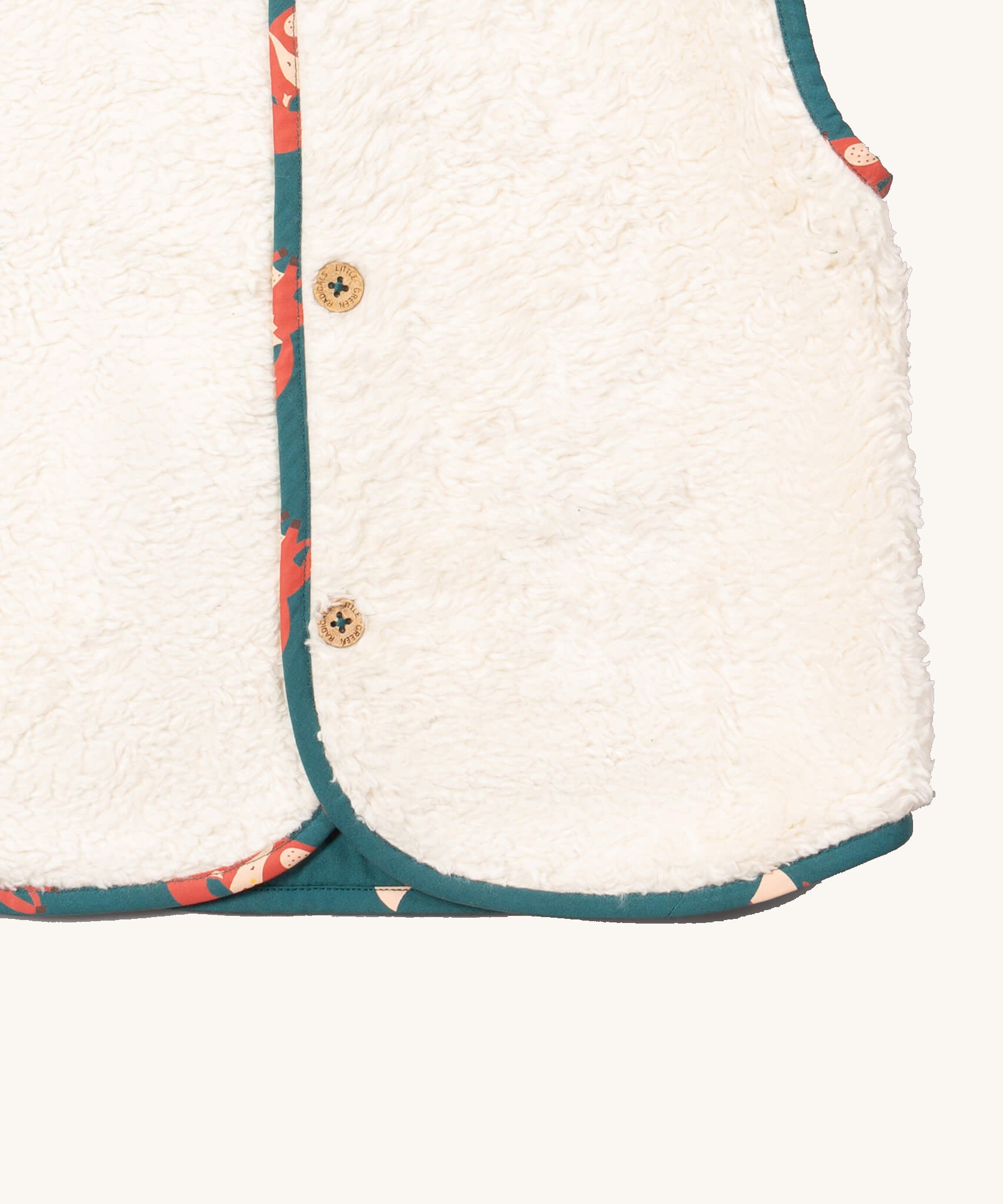 A close up of the Little Green Radicals reversible gilet in red foxes and sherpa lined. Showing the white sherpa fleece detail 