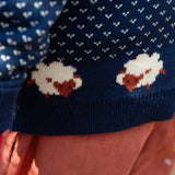 A close up of the Little Green Radicals navy snuggle knitted jumper with a cute sheep design showing the knit detail and a close up of the white speckles and sheep knitted in the jumper. 