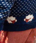 A close up of the Little Green Radicals navy snuggle knitted jumper with a cute sheep design showing the knit detail and a close up of the white speckles and sheep knitted in the jumper. 