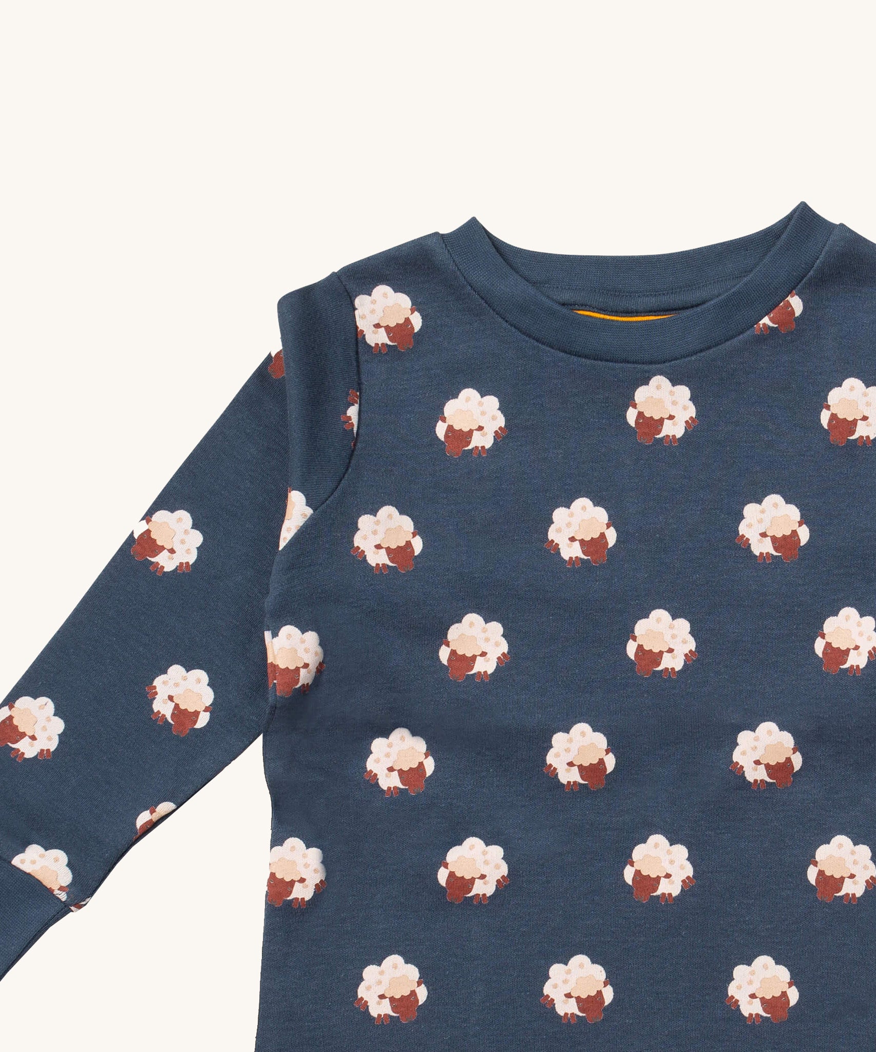A close up of the Little Green Radicals sleeping sheep pyjama top showing the navy collar detail with a close up of the white sheep print on navy organic cotton fabric.
