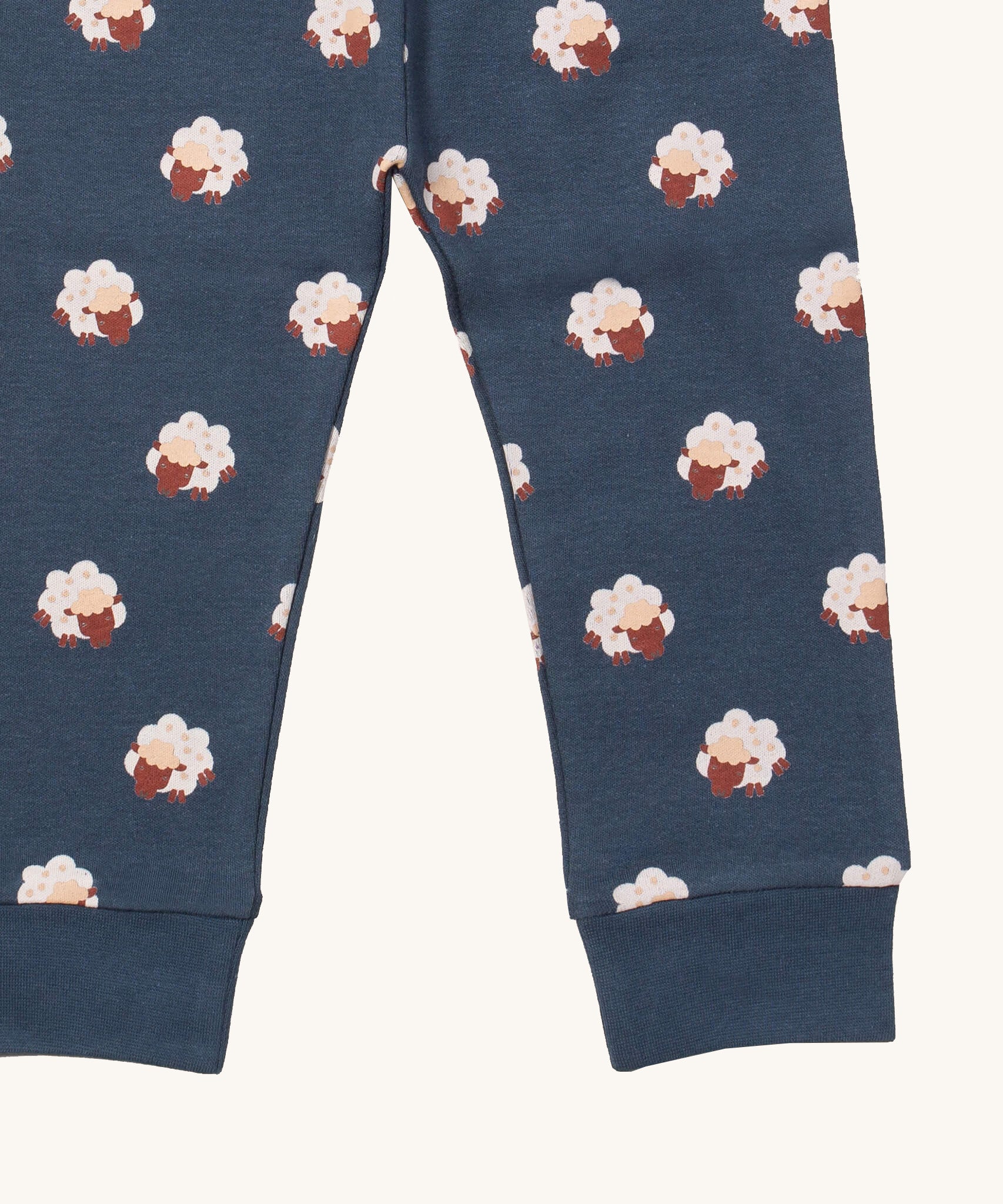 A close up of the Little Green Radicals sleeping sheep pyjama bottom. Showing the navy cuff detail with a close up of the white sheep print on navy organic cotton fabric.
