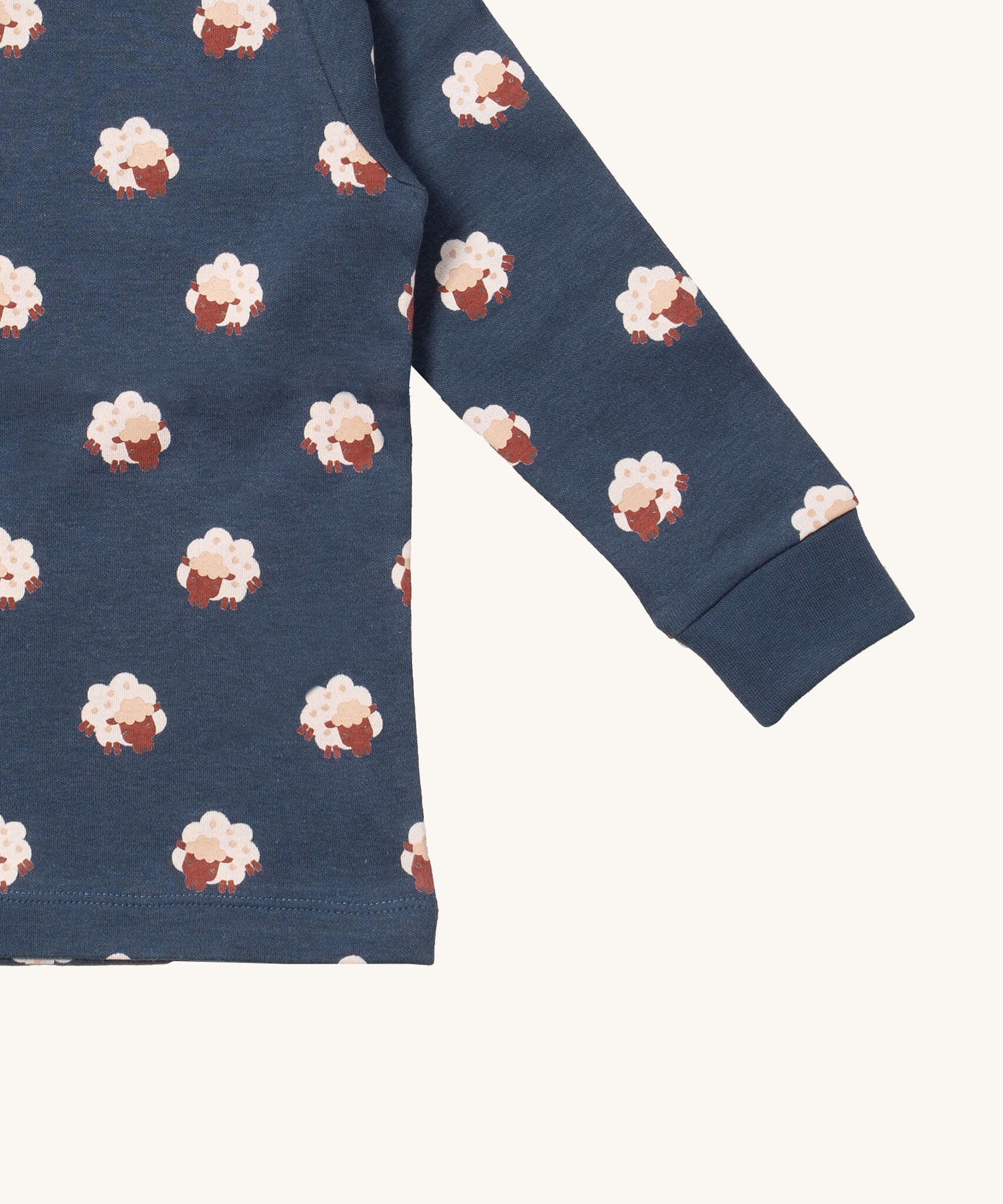 A close up of the Little Green Radicals sleeping sheep top showing the navy elasticated cuff detail with a close up of the white sheep print on navy organic cotton fabric.