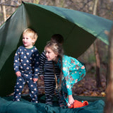 Children standing outside a tent in the forest. They are all wearing Little Green Radicals organic cotton pyjamas. One is wearing a pair with the Winter Rabbit on them, one in wearing navy and white striped design and the third is wearing the sleeping sheep print. Little green Radicals have a wide range of organic cotton, Fairtrade children's clothing an outerwear available here at Babipur.