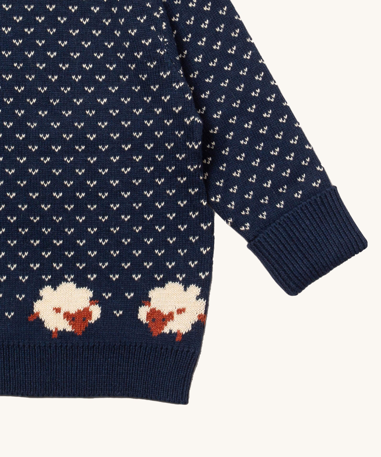 A close up of the Little Green Radicals navy sheep design showing the navy cuff and hem detail and a close up of the white speckles and sheep knitted in the jumper available at Babipur 