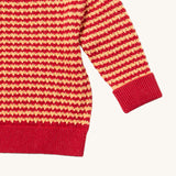 A close up of the Little Green Radicals snuggly knitted jumper in juniper stripe available at Babipur. Showing the yellow and pale red stripe knit detail and the matching pale red turned up cuff for size adjusting