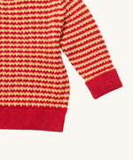 A close up of the Little Green Radicals snuggly knitted jumper in juniper stripe available at Babipur. Showing the yellow and pale red stripe knit detail and the matching pale red turned up cuff for size adjusting