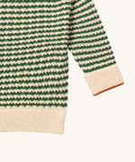 A close up of the Little Green Radicals snuggly knitted jumper in olive stripe available at Babipur. Showing the green and cream stripe knit detail and the matching cream turned up cuff for size adjusting