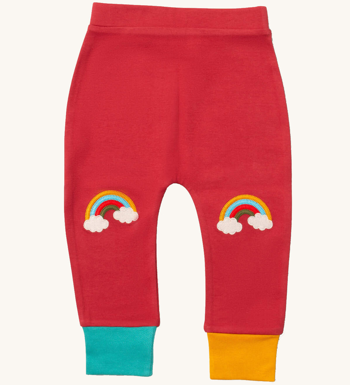 Little Green Radicals soft red rainbow kneepatch joggers available at Babipur. A soft GOTS organic cotton jogger in pale red with a blue and yellow leg cuff. Features a rainbow embroidery as knee patches. 