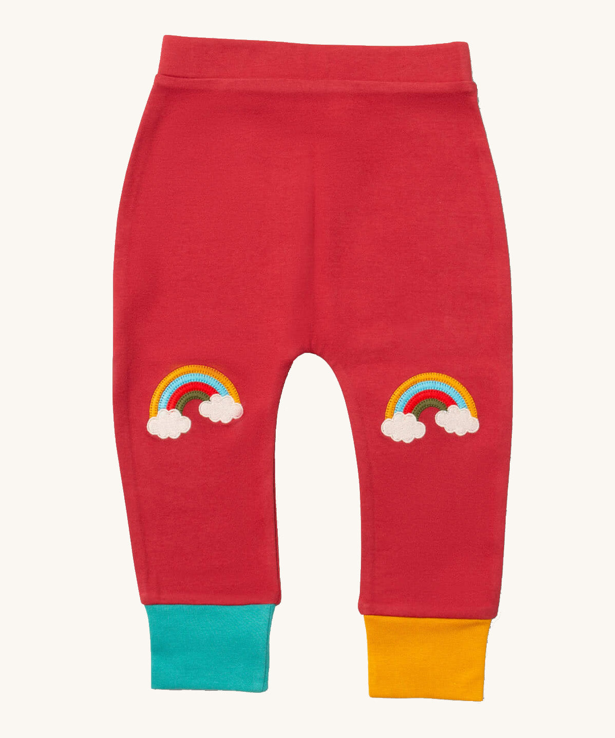 Little Green Radicals soft red rainbow kneepatch joggers available at Babipur. A soft GOTS organic cotton jogger in pale red with a blue and yellow leg cuff. Features a rainbow embroidery as knee patches. 