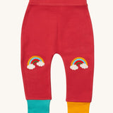 Little Green Radicals soft red rainbow kneepatch joggers available at Babipur. A soft GOTS organic cotton jogger in pale red with a blue and yellow leg cuff. Features a rainbow embroidery as knee patches. 