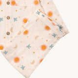 A close up of the Little Green Radicals classic moon and sun pyjama set showing the light pink organic cotton bottoms laid on top of the matching pyjama top.