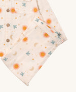 A close up of the Little Green Radicals classic moon and sun pyjama set showing the light pink organic cotton bottoms laid on top of the matching pyjama top.