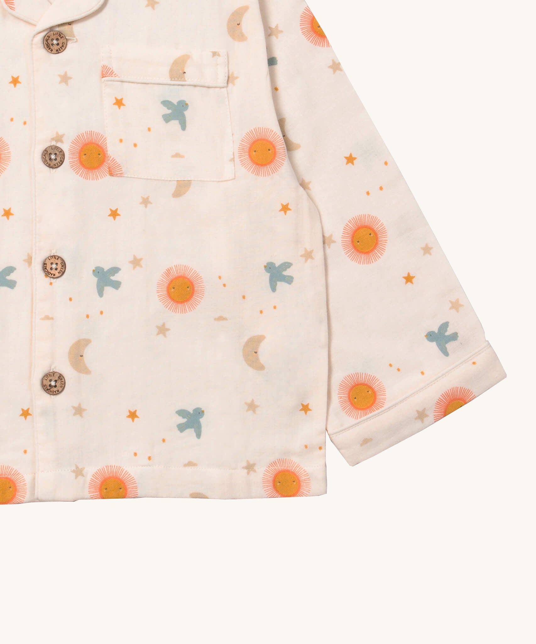 A close up of the Little Green Radicals classic pyjama top from the moon and sun classic set. showing the pocket and button fastener detail on light pink organic cotton fabric.