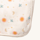 A close up of the sun and moon Little Green Radicals hooded blanket. Showing the cute sun and moon print detail and white trim detail on white organic cotton fabric