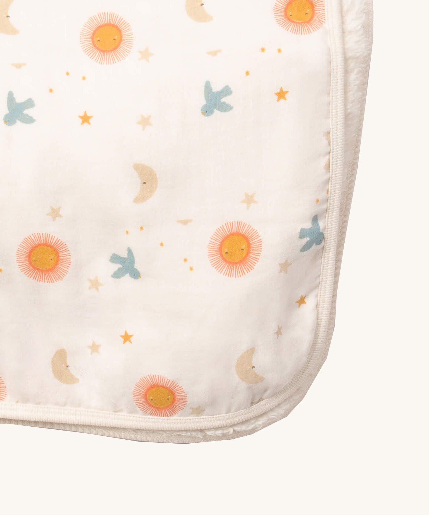 A close up of the sun and moon Little Green Radicals hooded blanket. Showing the cute sun and moon print detail and white trim detail on white organic cotton fabric
