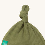A close up of the Little Green Radicals chiv waffle tie hat showing the knot detail and waffle knit on green organic cotton fabric