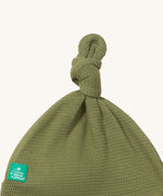 A close up of the Little Green Radicals chiv waffle tie hat showing the knot detail and waffle knit on green organic cotton fabric