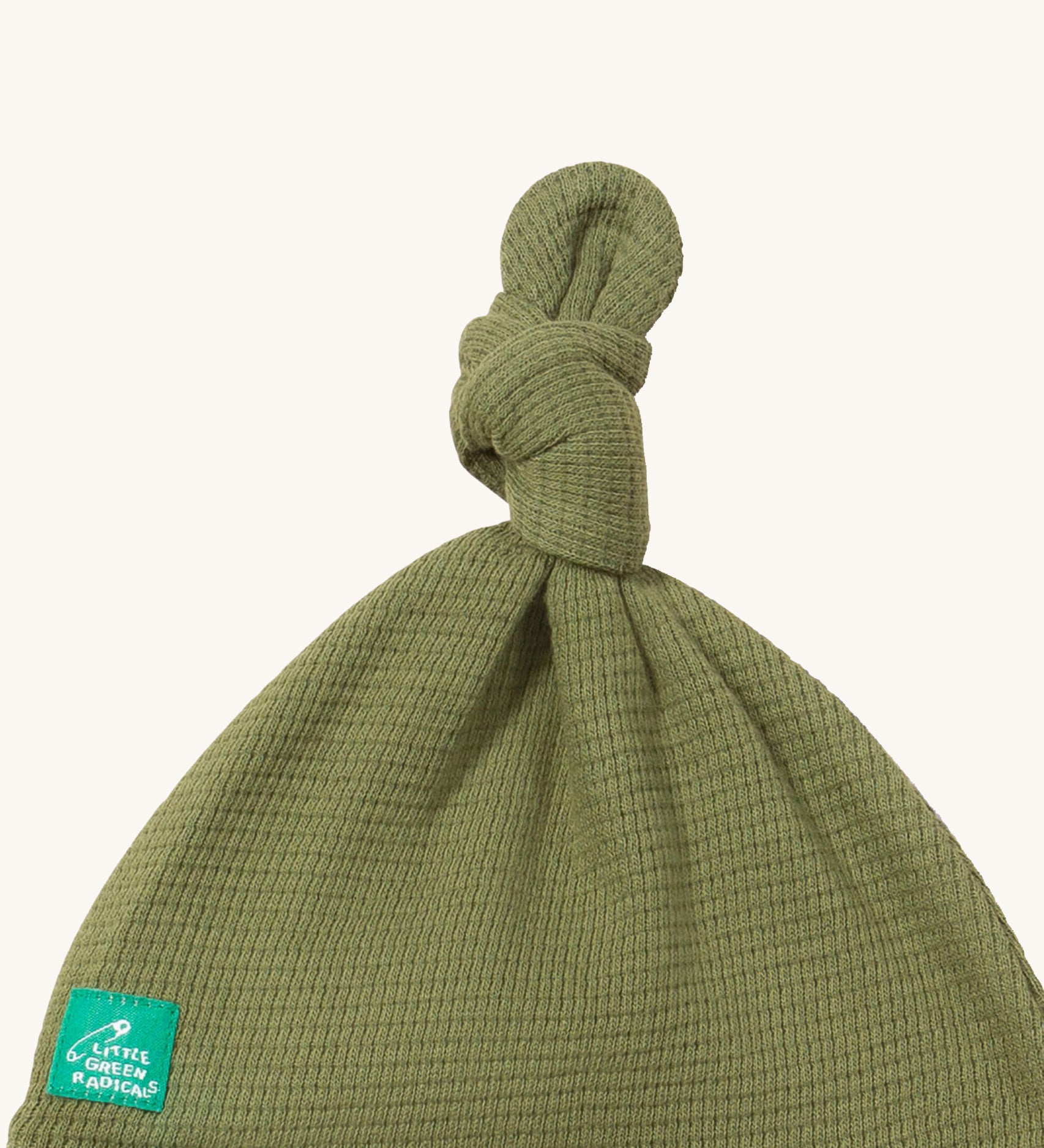 A close up of the Little Green Radicals chiv waffle tie hat showing the knot detail and waffle knit on green organic cotton fabric