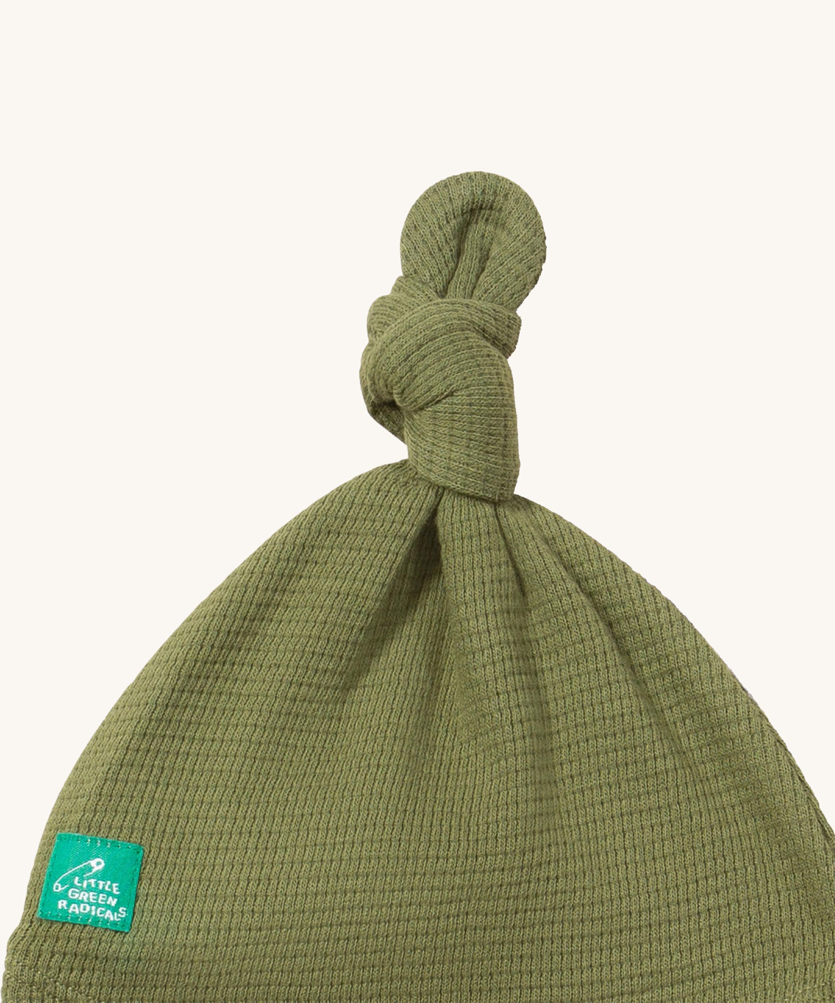 A close up of the Little Green Radicals chiv waffle tie hat showing the knot detail and waffle knit on green organic cotton fabric