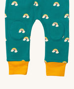 A close up  the Little Green Radicals turquoise rainbow joggers showing the stitched on knee patches  and yellow cuff trim on organic cotton fabric