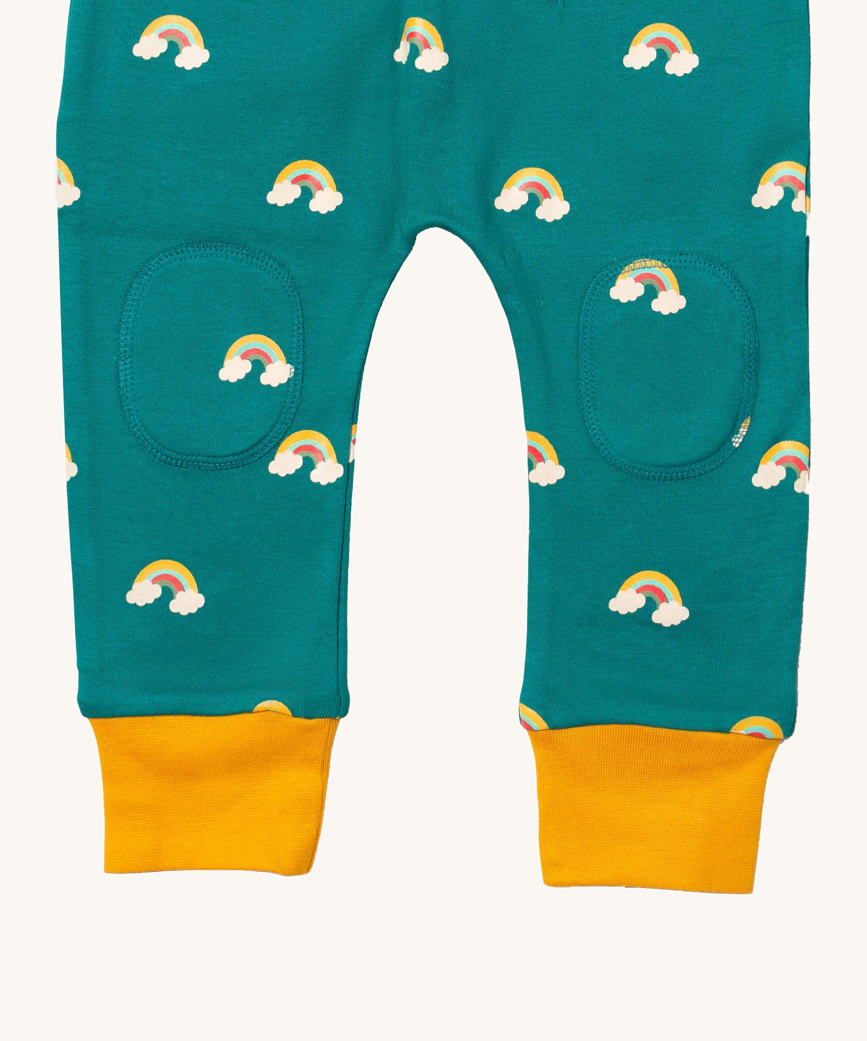 A close up  the Little Green Radicals turquoise rainbow joggers showing the stitched on knee patches  and yellow cuff trim on organic cotton fabric