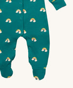 A close up of the Little Green Radicals turquoise rainbow baby grow, showing the popper fastener detail around the crotch on turquoise organic cotton fabric with cute rainbow prints.
