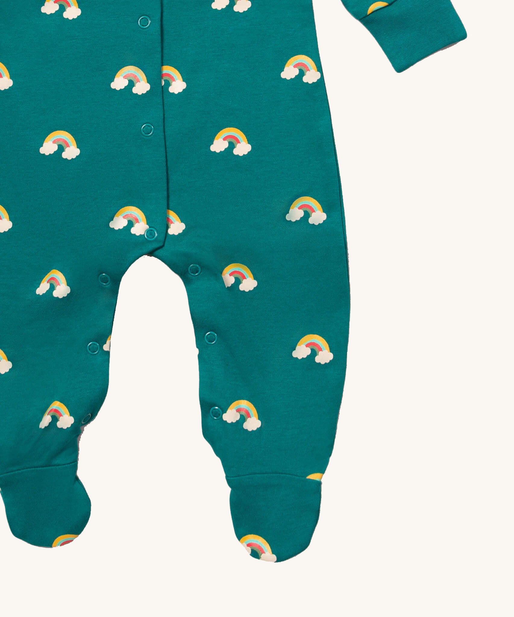 A close up of the Little Green Radicals turquoise rainbow baby grow, showing the popper fastener detail around the crotch on turquoise organic cotton fabric with cute rainbow prints.