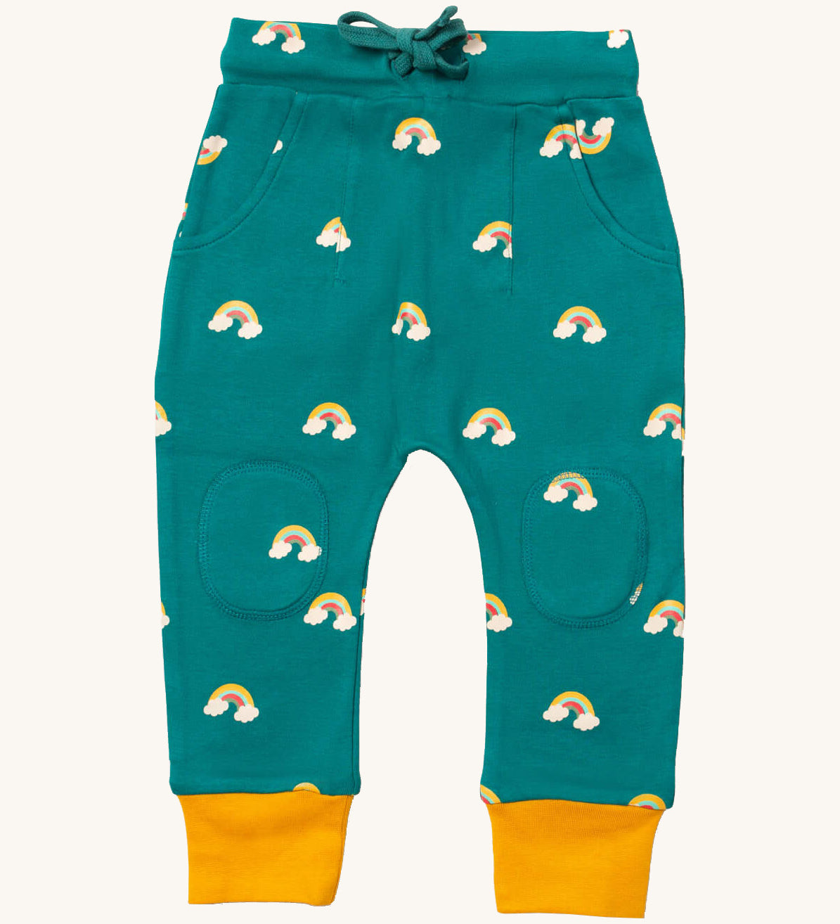 Little Green Radicals comfy joggers in turquoise rainbow available at Babipur.. A soft GOTS organic cotton turquoise jogger pants with yellow trim and cute rainbow prints. Features 2 side pockets a matching navy waist drawstring and knee patches.