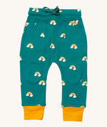 Little Green Radicals comfy joggers in turquoise rainbow available at Babipur.. A soft GOTS organic cotton turquoise jogger pants with yellow trim and cute rainbow prints. Features 2 side pockets a matching navy waist drawstring and knee patches.