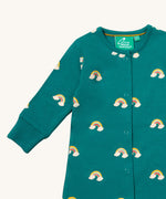 A close up of the Little Green Radicals turquoise rainbow baby grow, showing the popper fastener detail on turquoise organic cotton fabric.