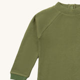 A close up of the Little Green Radicals green chive waffle long sleeve cosy top showing the waffle and popper fastener detail on green organic cotton fabric