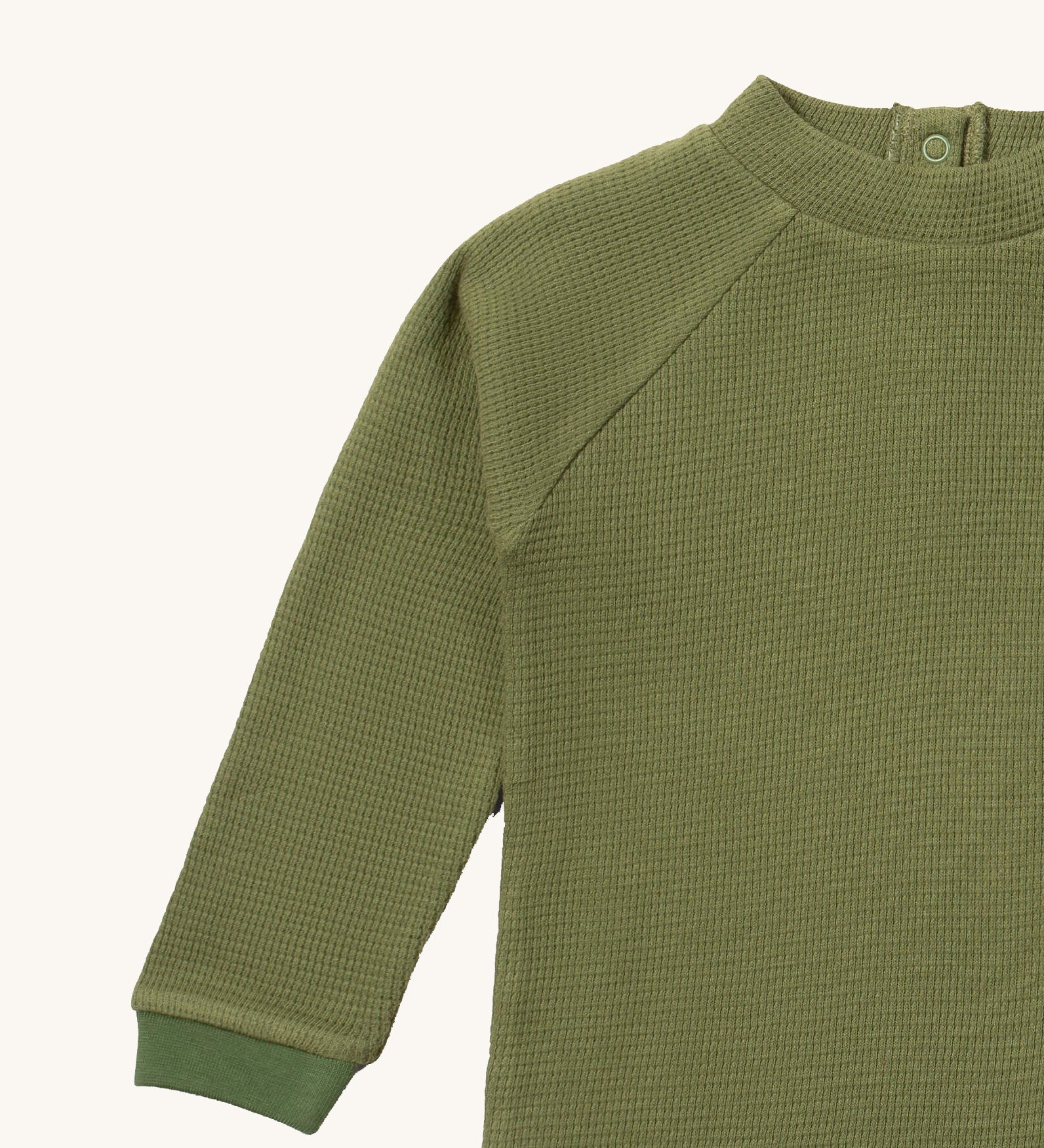 A close up of the Little Green Radicals green chive waffle long sleeve cosy top showing the waffle and popper fastener detail on green organic cotton fabric