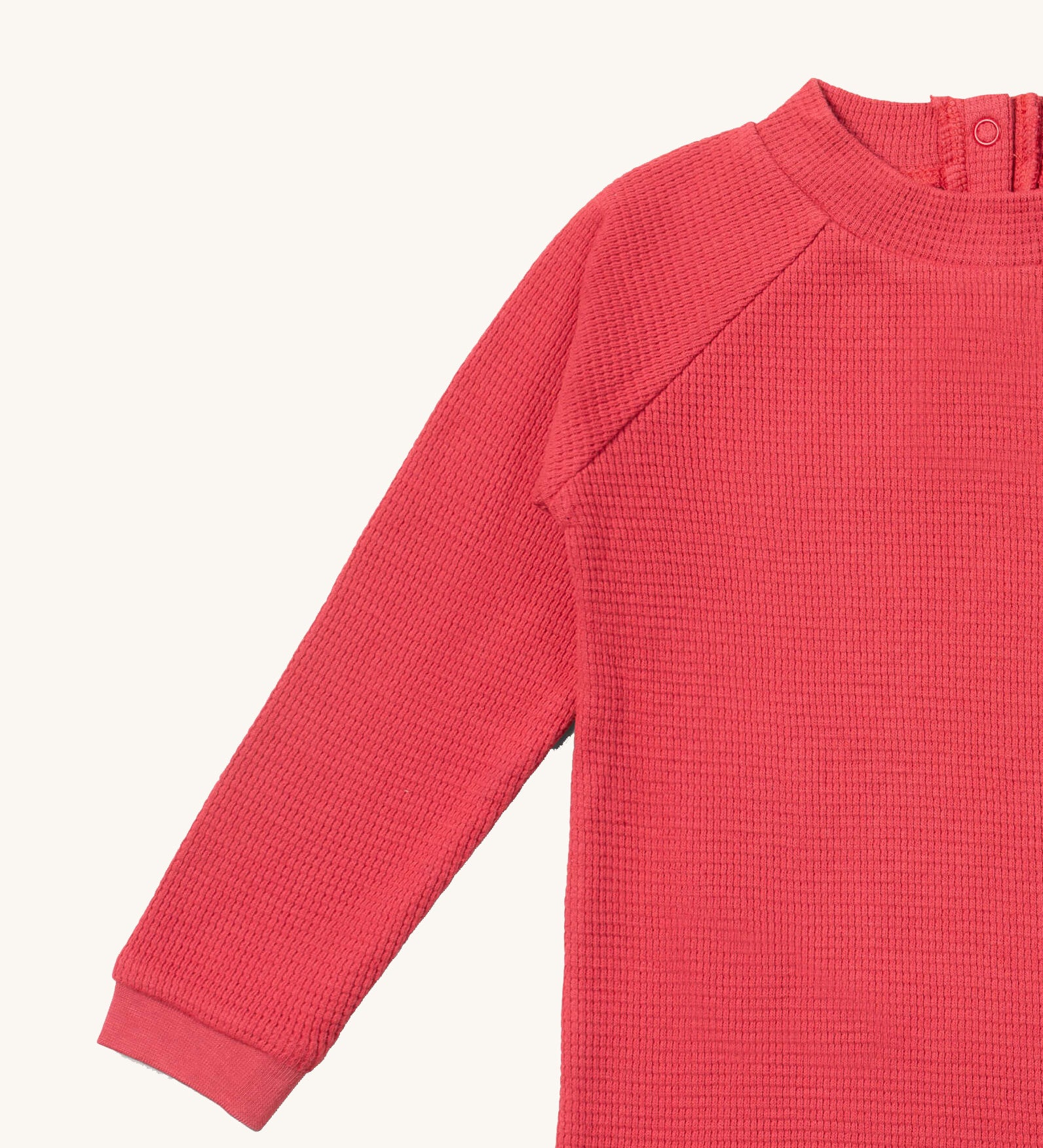 A close up of the Little Green Radicals pink berry waffle long sleeve cosy top showing the waffle and popper fastener detail on pink organic cotton fabric