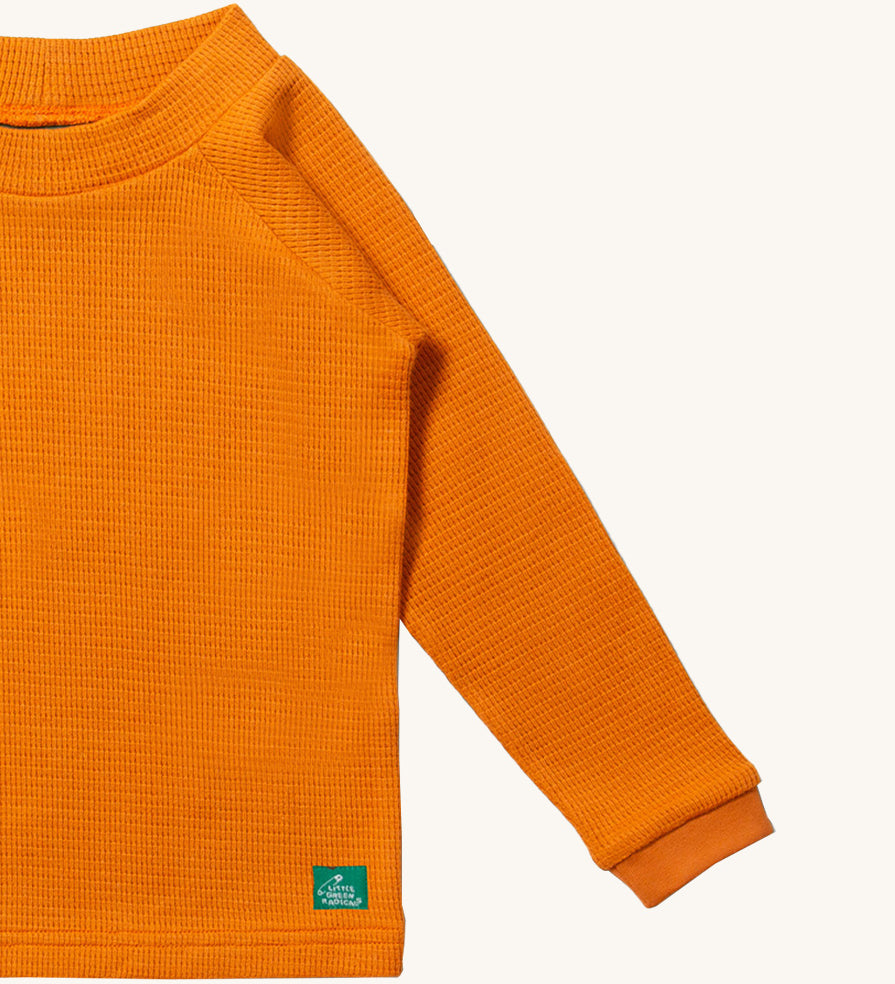 A close up of LGR Long Sleeve Waffle Top - Golden Ochre showing the waffle texture detail on yellow organic cotton fabric