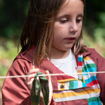 A closer look at the side of the Little Green Radicals Rainbow Striped Recycled Waterproof Windbreaker Jacket on a child
