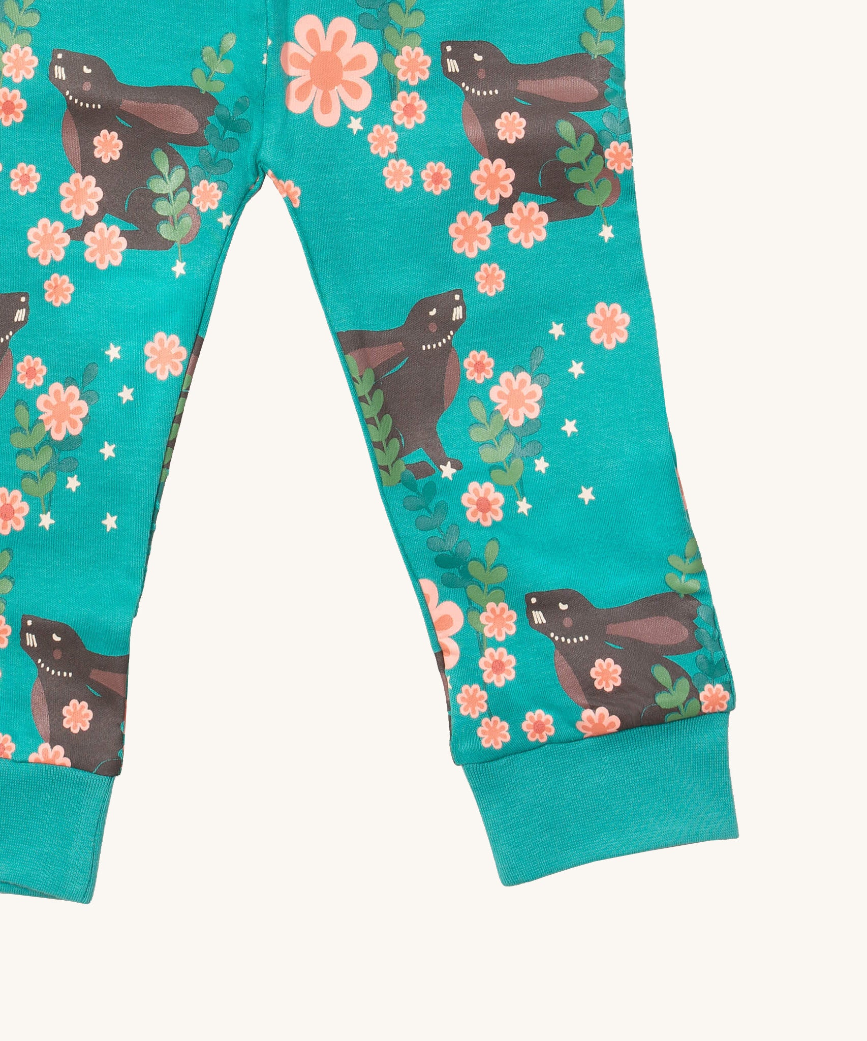 A close up of the Little Green Radicals winter rabbit pyjama bottom. Showing the turquoise cuff detail with a close up of the brown rabbit in pink flowers print on turquoise organic cotton fabric.