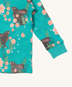 A close up of the Little Green Radicals winter rabbit top showing the turquoise elasticated cuff detail with a close up of the brown rabbit in pink flowers print on turquoise organic cotton fabric.