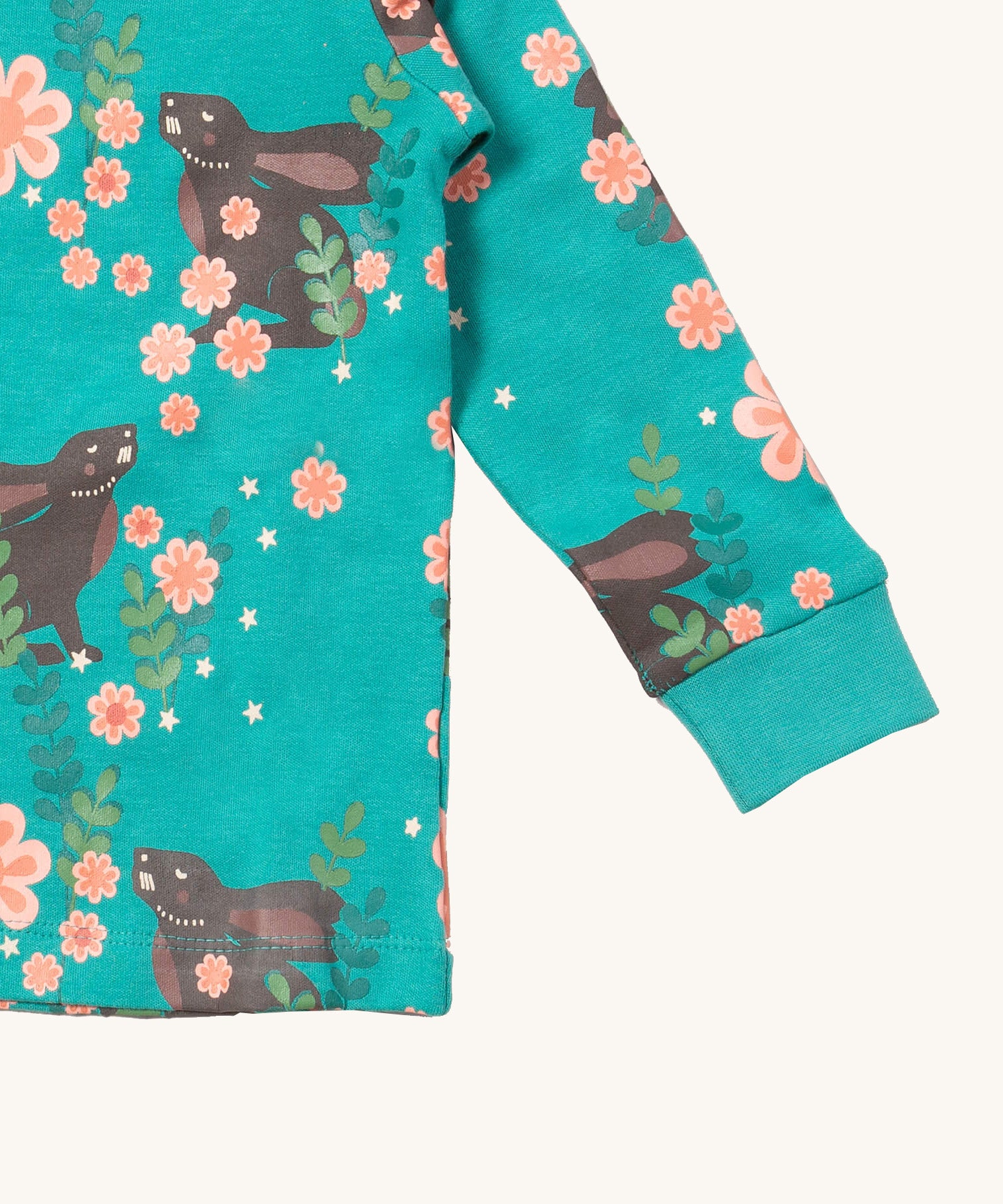A close up of the Little Green Radicals winter rabbit top showing the turquoise elasticated cuff detail with a close up of the brown rabbit in pink flowers print on turquoise organic cotton fabric.