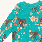 A close up of the Little Green Radicals winter rabbit pyjama top showing the turquoise collar detail with a close up of the brown rabbit print in pink flowers on organic cotton fabric.