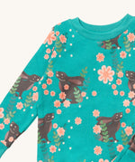 A close up of the Little Green Radicals winter rabbit pyjama top showing the turquoise collar detail with a close up of the brown rabbit print in pink flowers on organic cotton fabric.