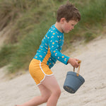 Boy running on some sand wearing the yellow LGR kids swimming shorts
