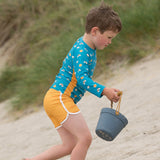 Boy running on some sand wearing the yellow LGR kids swimming shorts