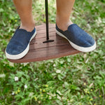 Close up of a boys shoes stood on the Lillagunga walnut wood disco swing