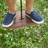 Close up of a boys shoes stood on the Lillagunga walnut wood disco swing