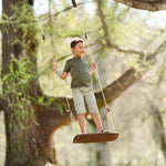 Boy stood on the Lillagunga walnut grand swing hanging from a large tree in a park