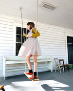 Girl stood on the Lillagunga oak wood grand swing on a wooden porch