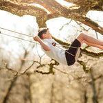 Boy sat swinging on a Lillagunga grand swing in the branches of a tall tree